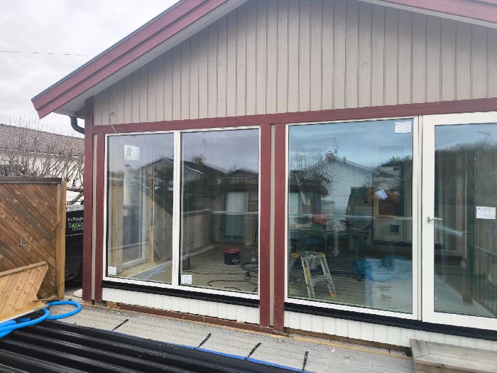 Pågående fönsterbyte på hus i Eskilstuna med stora nya glaspartier installerade och verktyg synliga på altanen.