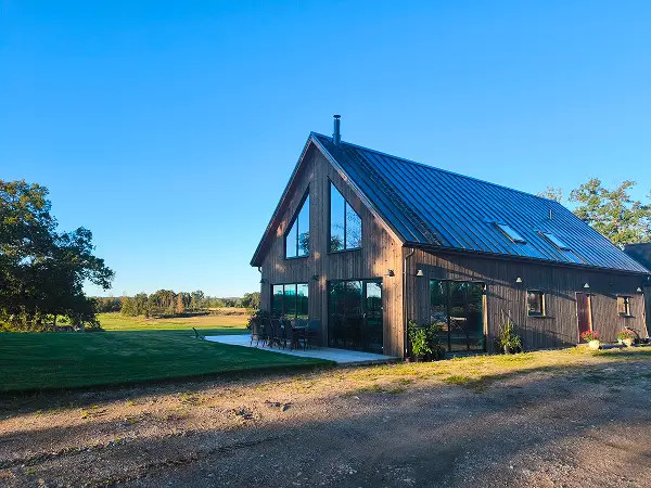 Modernt trähus med svart plåttak och rörröd entrédörr i Eskilstuna, byggt av lokal byggfirma med fokus på kvalitet och helhetslösningar.